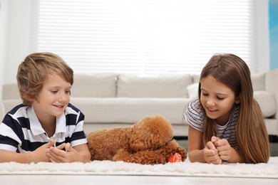 Little children and cute puppy on carpet at home. Lovely pet