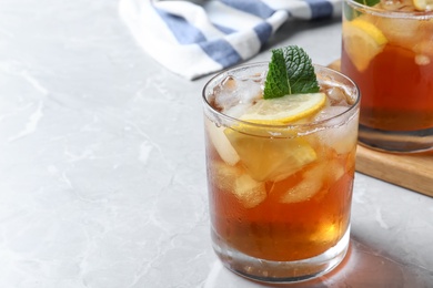 Photo of Delicious iced tea in glass on light grey marble table. Space for text