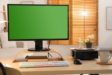 Photo of Modern computer and RGB keyboard on wooden table indoors. Mockup green screen