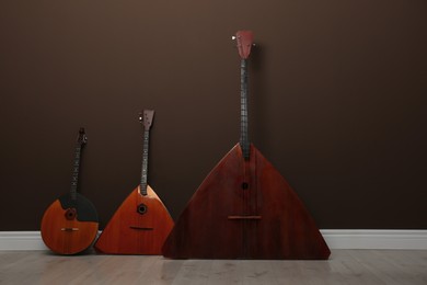 Photo of Set of folk string musical instruments near brown wall indoors. Space for text