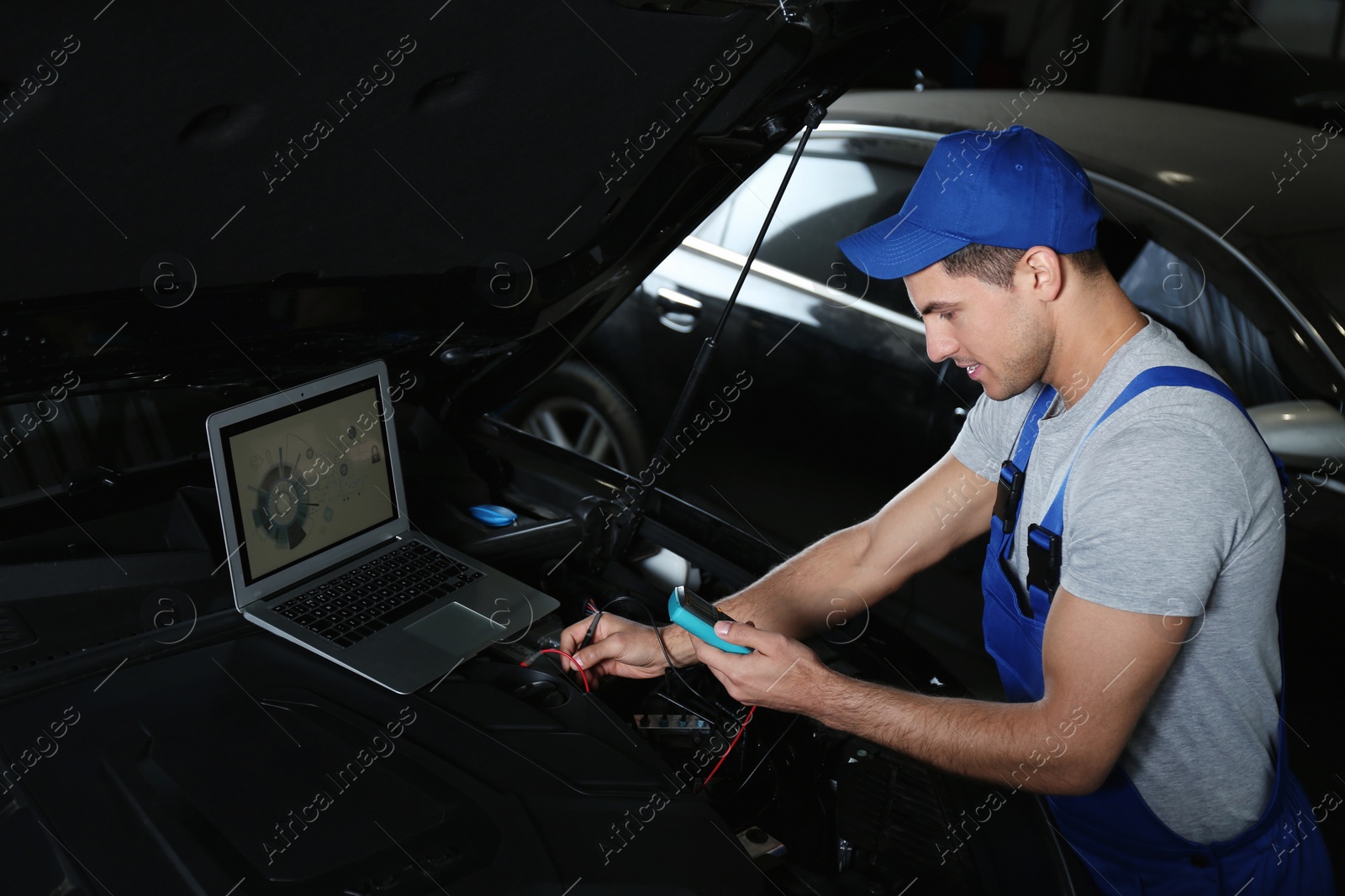 Photo of Mechanic with laptop doing car diagnostic at automobile repair shop