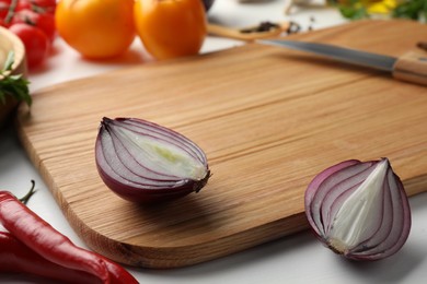 Cutting board with different vegetables and knife on white wooden table, closeup