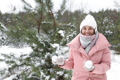 Photo of Beautiful young woman with snowballs in winter forest