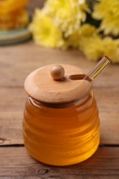 Photo of Sweet golden honey in jar on wooden table