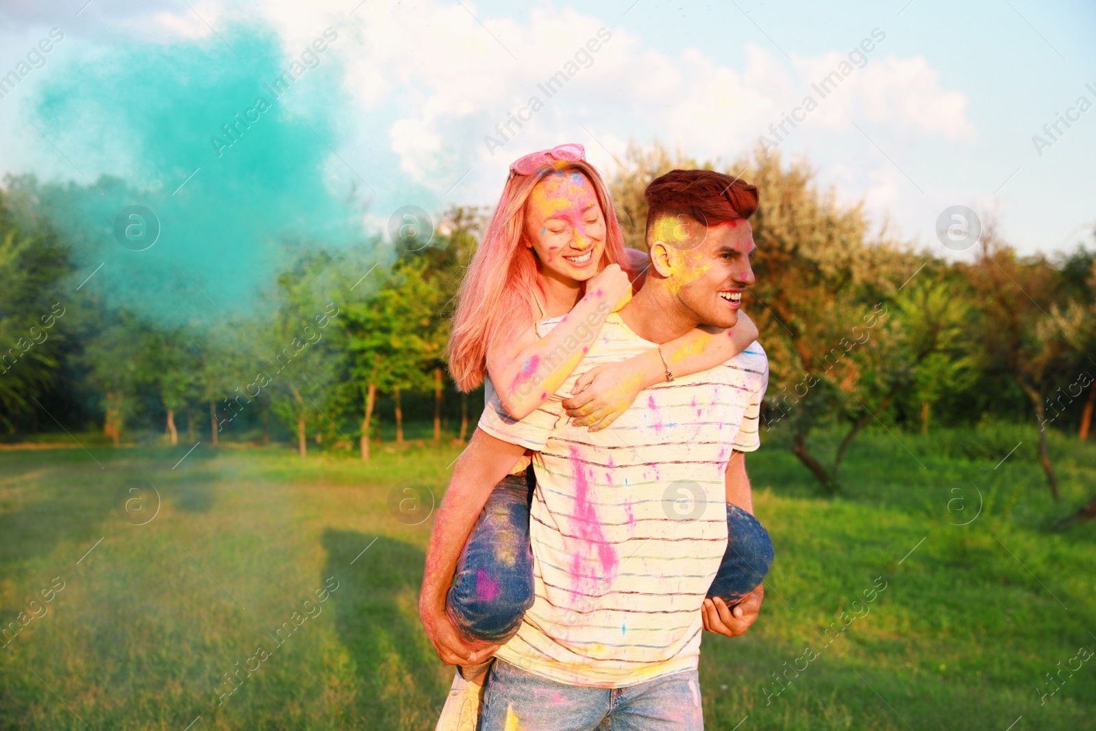 Photo of Happy couple covered with colorful powder dyes outdoors. Holi festival celebration