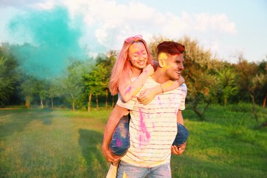 Happy couple covered with colorful powder dyes outdoors. Holi festival celebration