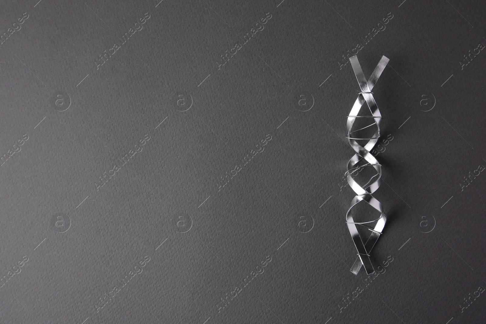 Photo of DNA molecular chain model made of metal on grey background, top view. Space for text