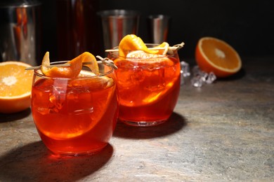 Photo of Aperol spritz cocktail, ice cubes and orange slices in glasses on grey textured table, closeup. Space for text