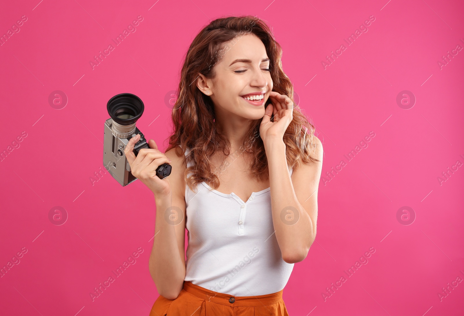 Photo of Beautiful young woman with vintage video camera on crimson background