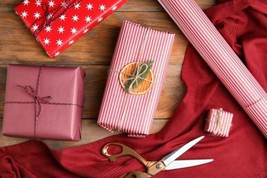 Flat lay composition of Christmas gift boxes wrapped with color paper on wooden table