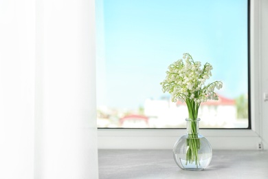 Beautiful lily of the valley bouquet in vase on windowsill, space for text