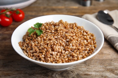 Dish of buckwheat porridge with parsley on wooden table