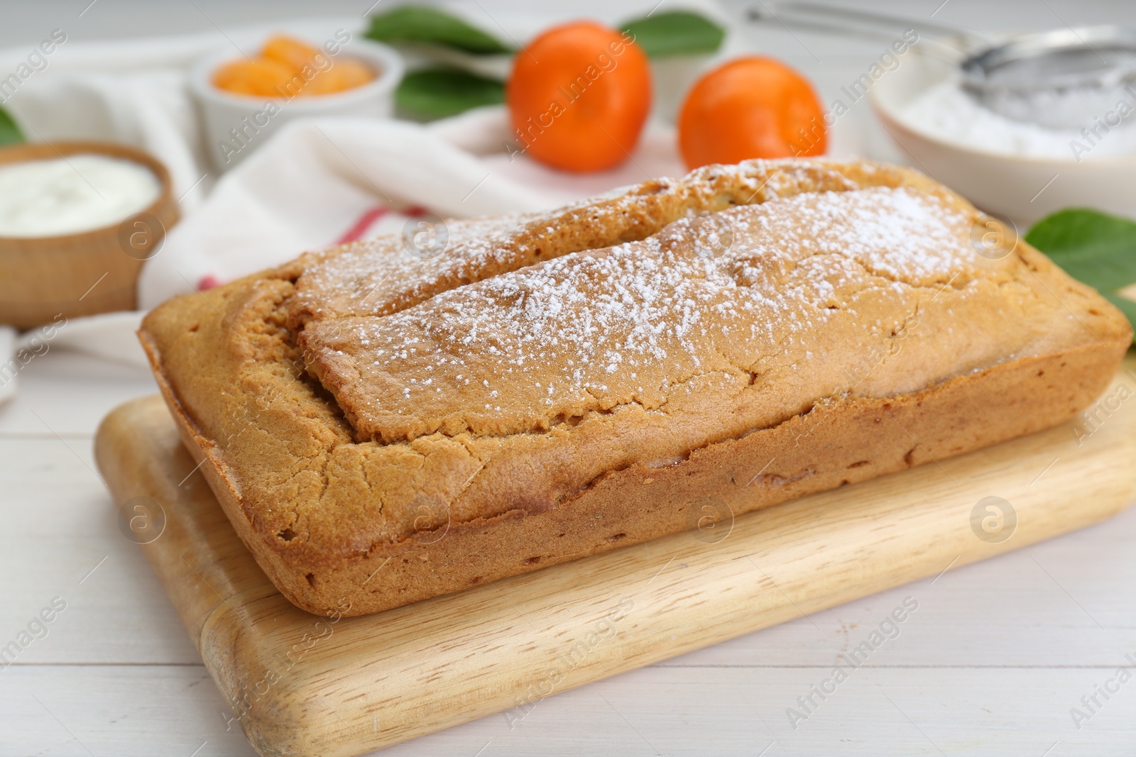 Photo of Delicious homemade yogurt cake with powdered sugar on white wooden table, closeup