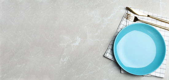 Photo of Empty blue plate with cutlery and napkin on light grey marble table, flat lay. Space for text