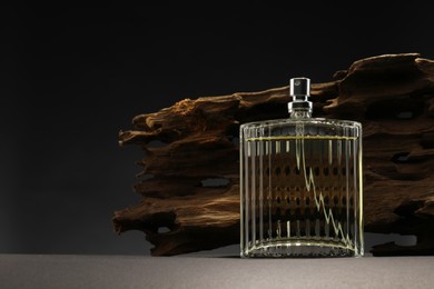 Photo of Luxury men`s perfume in bottle on grey table against dark background, space for text