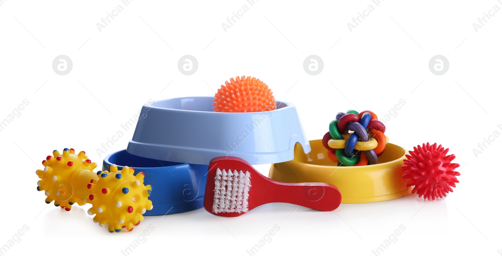 Photo of Feeding bowls, brush and dog toys on white background