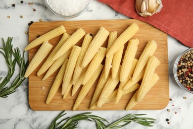 Photo of Fresh baby corn cobs and spices on white marble table, flat lay