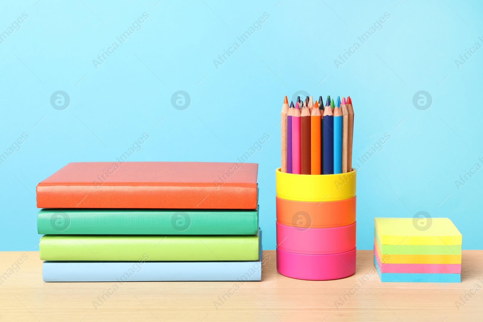 Photo of Composition with different school stationery on wooden table against light blue background. Back to school