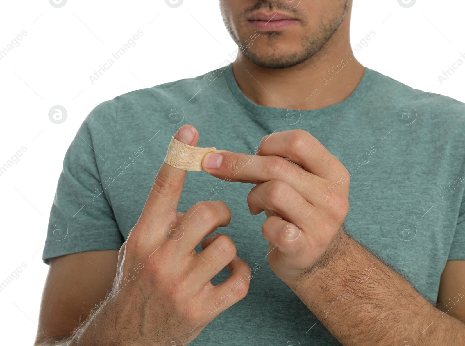 Photo of Man putting sticking plaster onto finger on white background, closeup