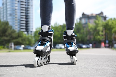 Photo of Woman with modern inline roller skates in city park, closeup