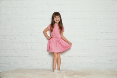 Photo of Portrait of cute little girl against brick wall