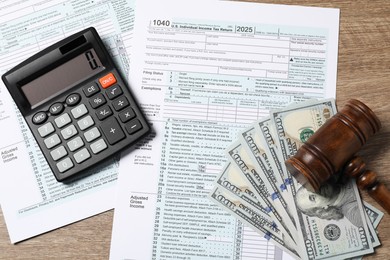 Photo of Tax return forms, dollar banknotes, calculator and gavel on wooden table, top view