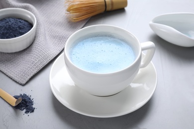 Blue matcha latte in cup on grey table