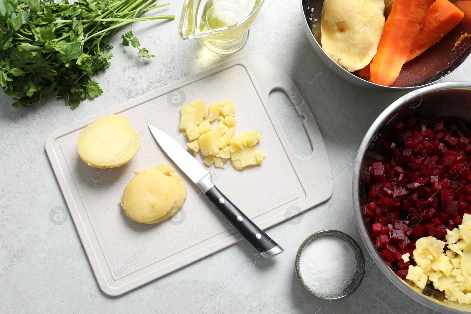 Photo of Cut boiled potatoes and ingredients on white table, flat lay. Cooking vinaigrette salad