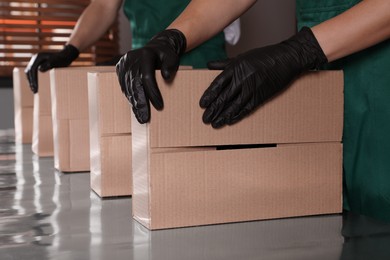 Photo of People packing cardboard boxes at production line indoors, closeup