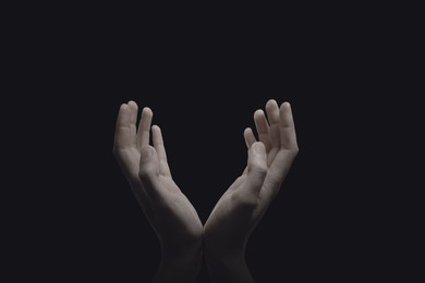 Christian man praying in darkness, closeup. Belief