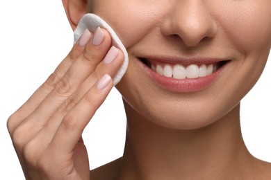 Smiling woman removing makeup with cotton pad on white background, closeup