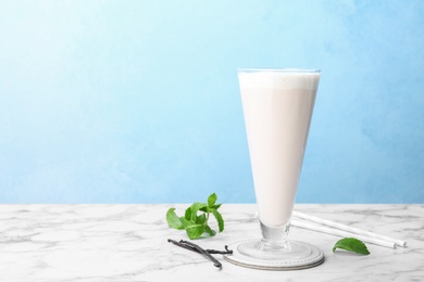 Glass with vanilla milk shake on table