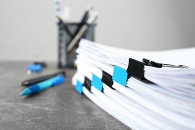 Photo of Stack of documents with binder clips on grey stone table, closeup view. Space for text