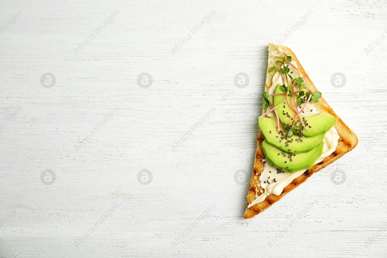 Photo of Tasty toast with avocado, sprouts and chia seeds on white wooden background, top view. Space for text