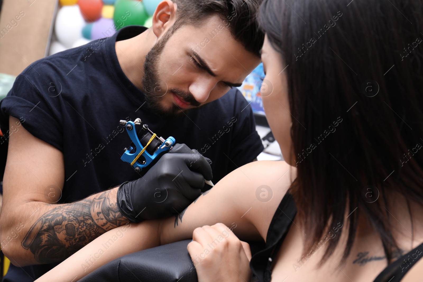 Photo of Professional artist making tattoo with machine in salon