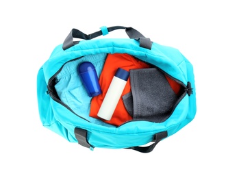 Photo of Sport bag with deodorants and clothes on white background, top view