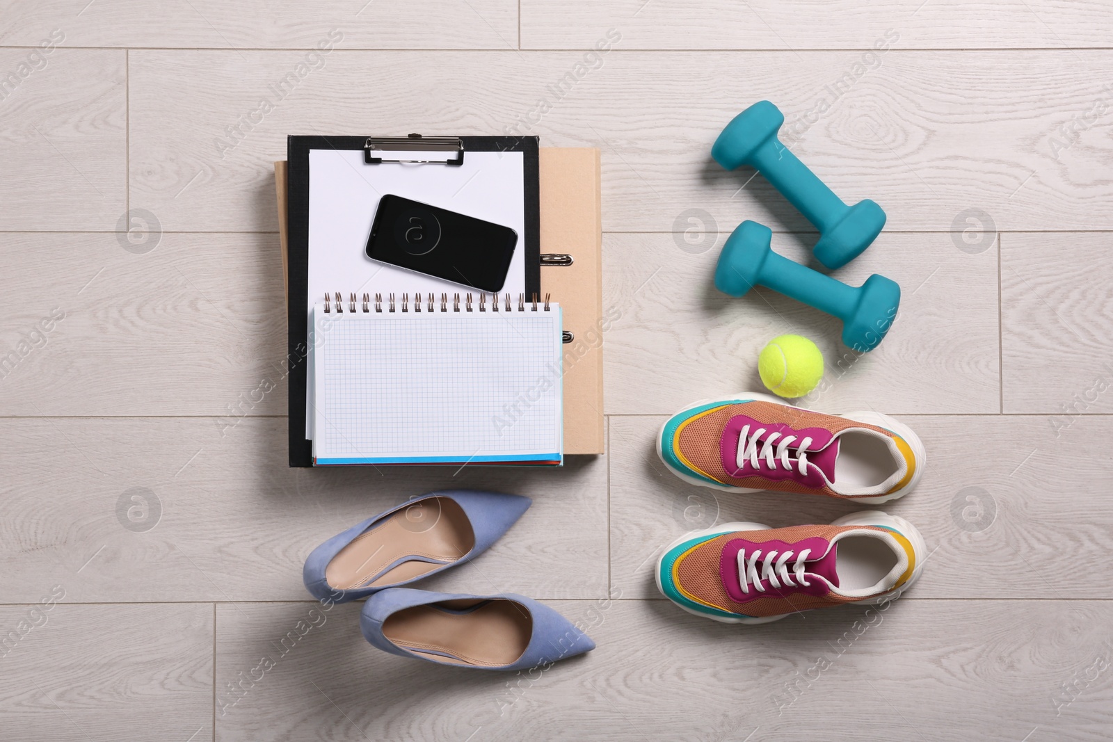 Photo of Flat lay composition with business supplies and sport equipment on white wooden floor. Concept of balance between work and life