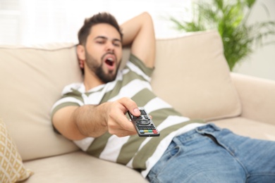 Photo of Lazy young man watching TV on sofa at home