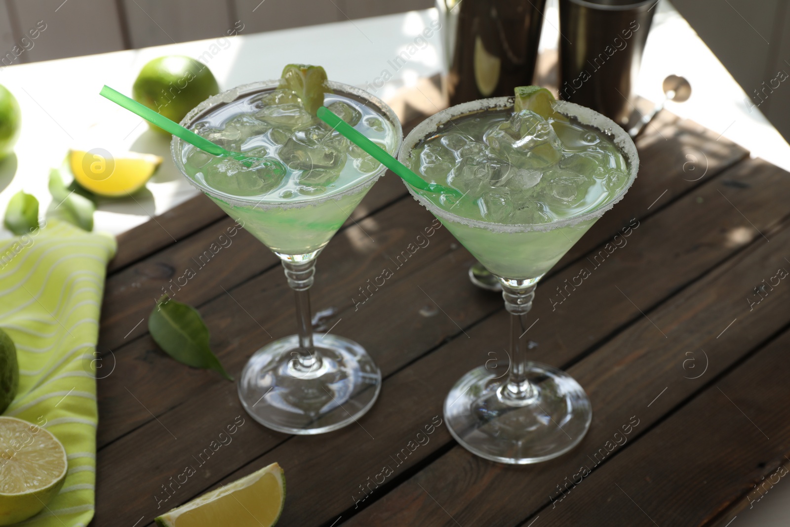 Photo of Delicious Margarita cocktail in glasses and lime on wooden table, closeup