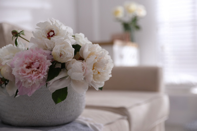 Photo of Bouquet of beautiful peony flowers in basket on sofa, closeup. Space for text