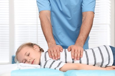 Photo of Orthopedist massaging child's back in clinic, closeup. Scoliosis treatment