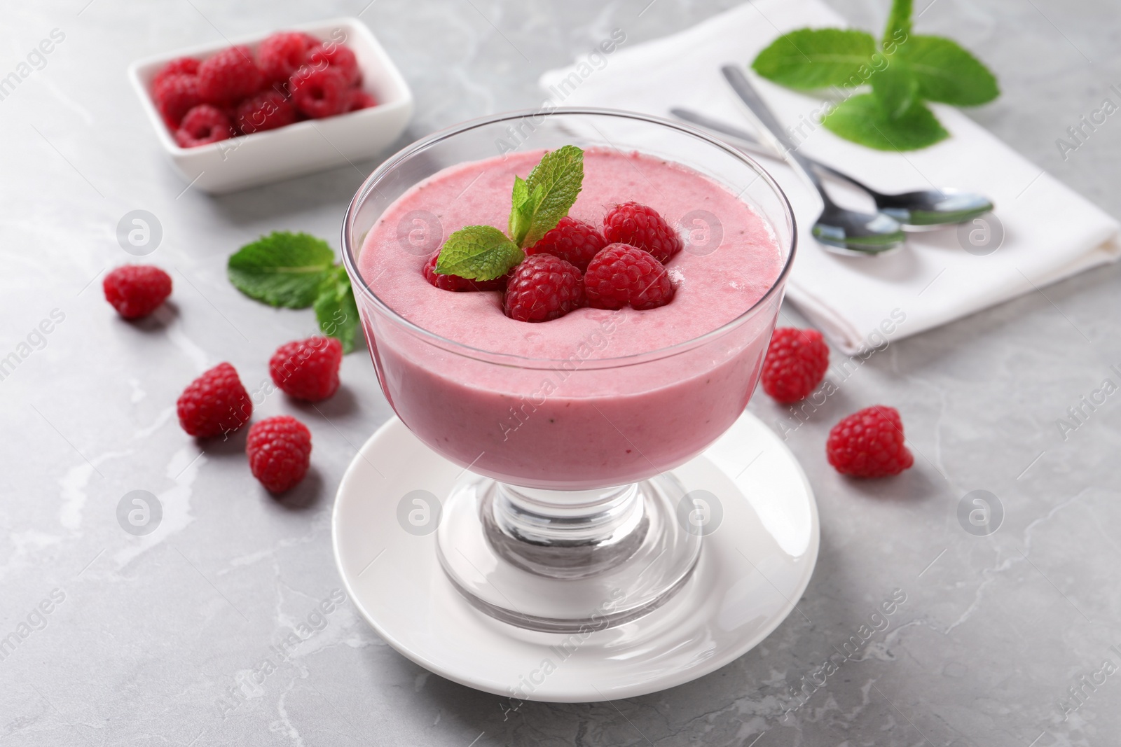 Photo of Delicious raspberry mousse with mint on grey marble table