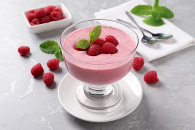 Photo of Delicious raspberry mousse with mint on grey marble table