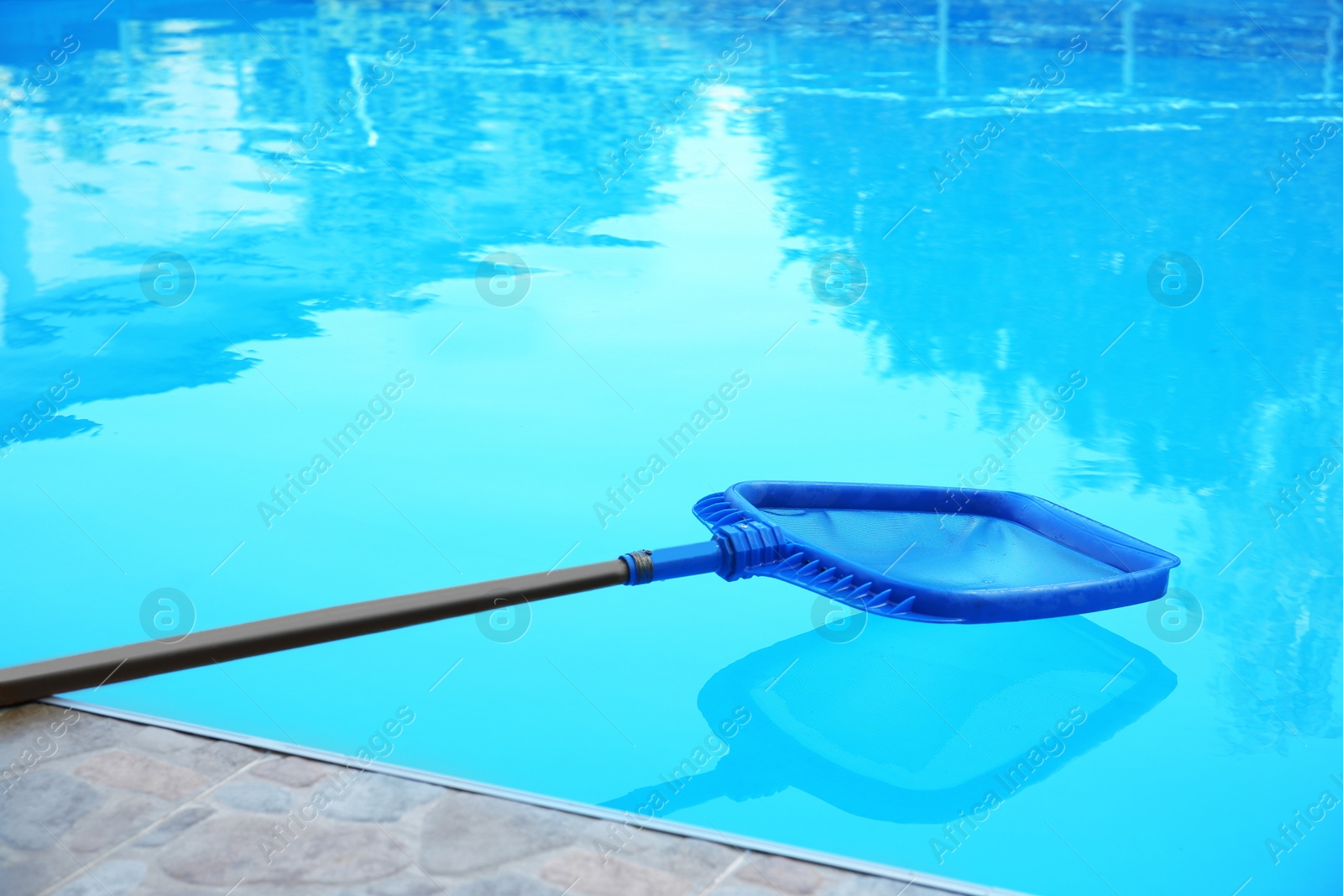 Photo of Cleaning outdoor pool with scoop net, closeup