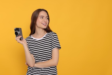 Photo of Young woman with camera on yellow background, space for text. Interesting hobby