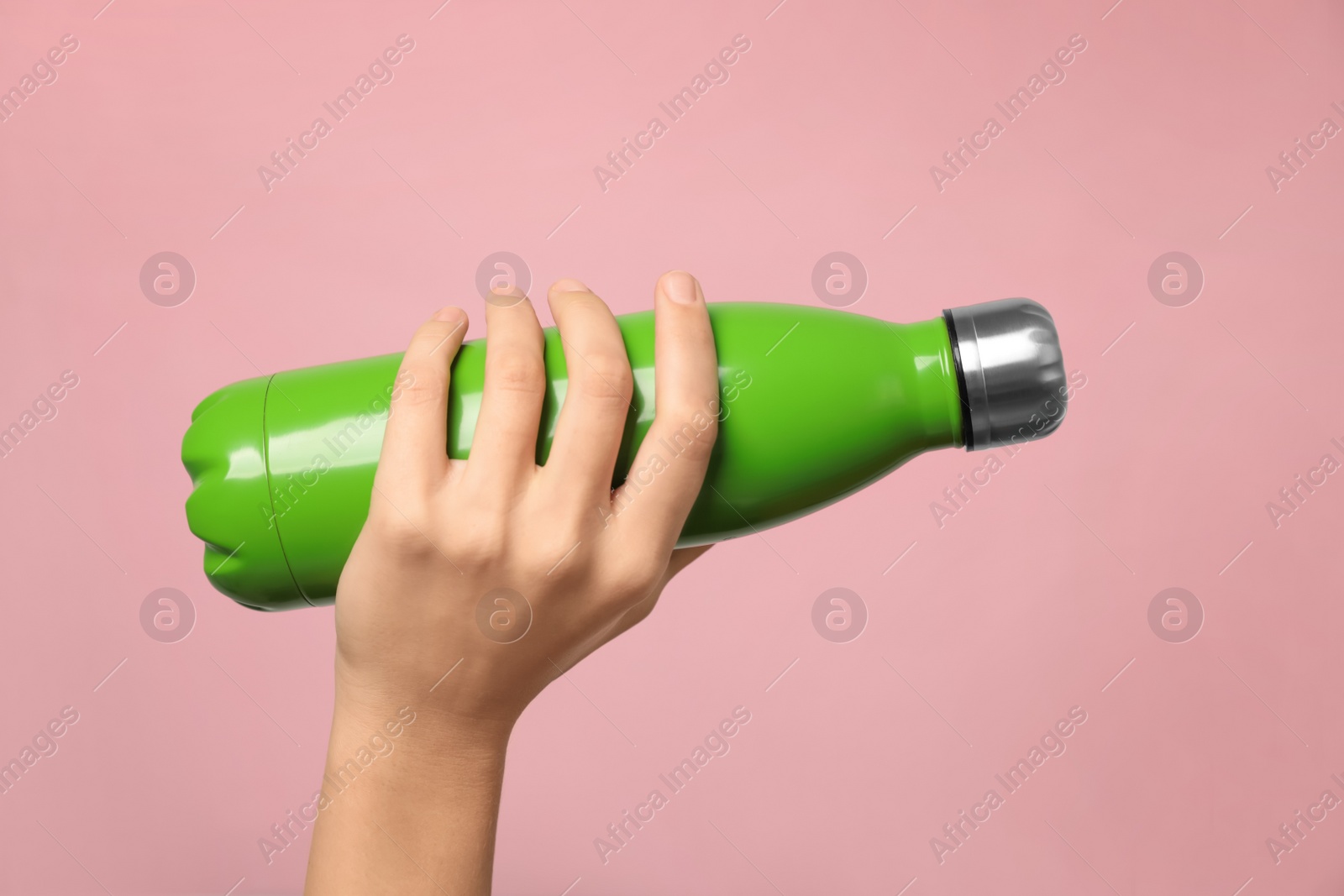 Photo of Woman holding modern green thermos on pink background, closeup