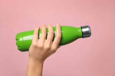 Woman holding modern green thermos on pink background, closeup