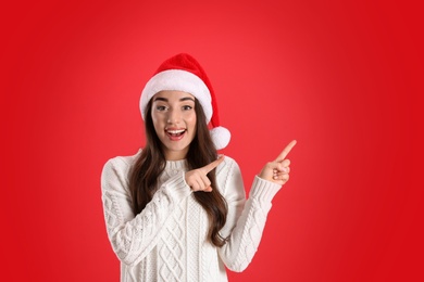 Photo of Beautiful woman wearing Santa Claus hat on red background