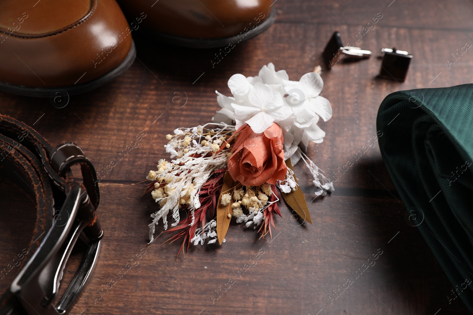 Photo of Wedding stuff. Composition with stylish boutonniere on wooden background