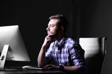 Photo of Concentrated young man working in office alone at night